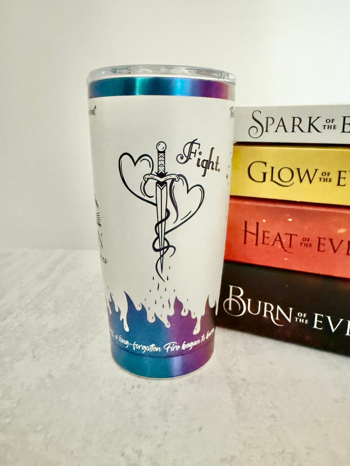 A white and rainbow Emarion 20 oz tumbler, showing the mating mark tattoo design and the word 'fight' from Burn of the Everflame by Penn Cole