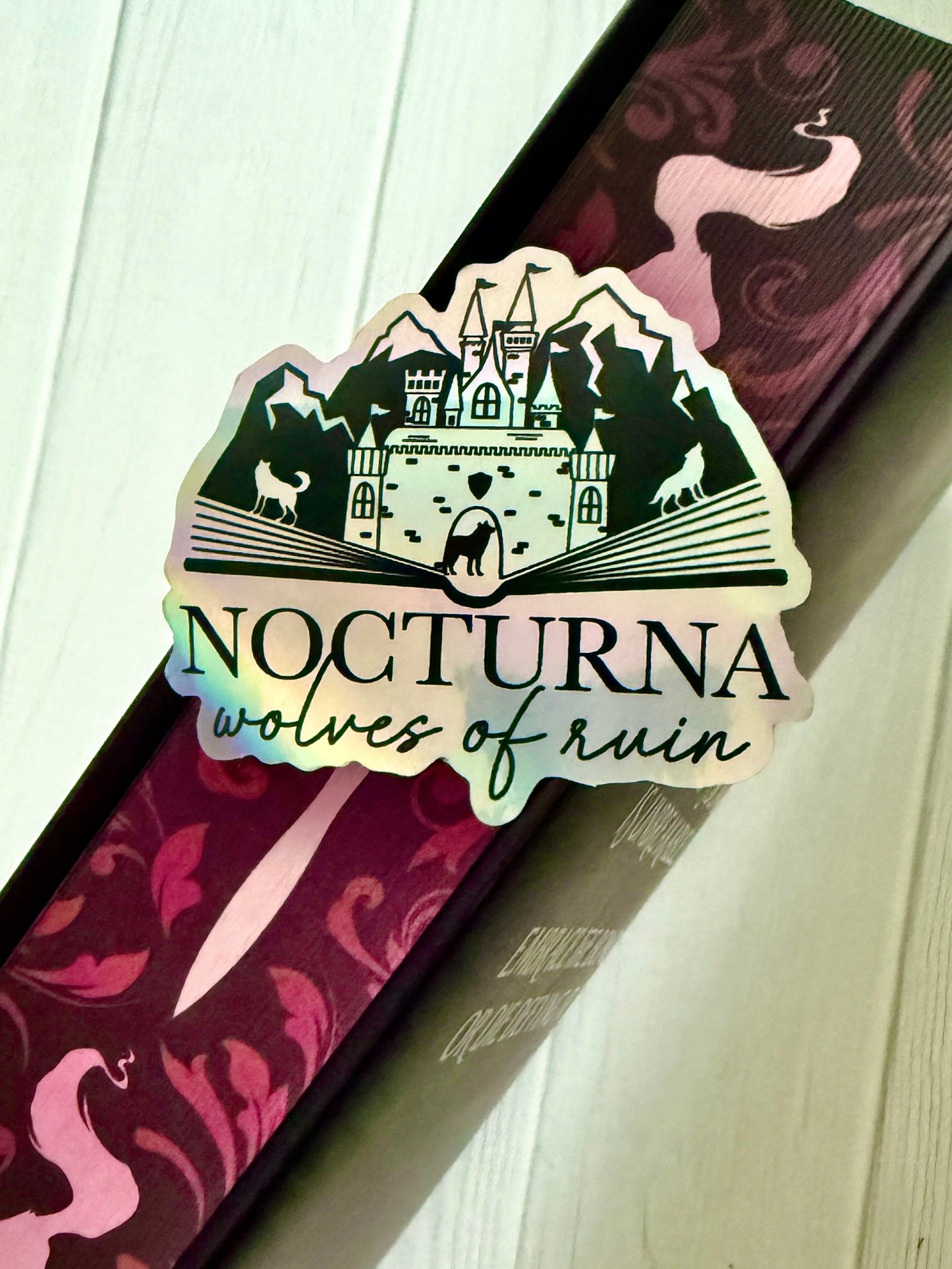 Sticker with 'Nocturna wolves of ruin' design on the sprayed edges of a Dire Bound book.