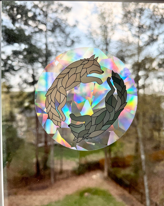 Holographic decal with two wolves on a window with a blurred outdoor background