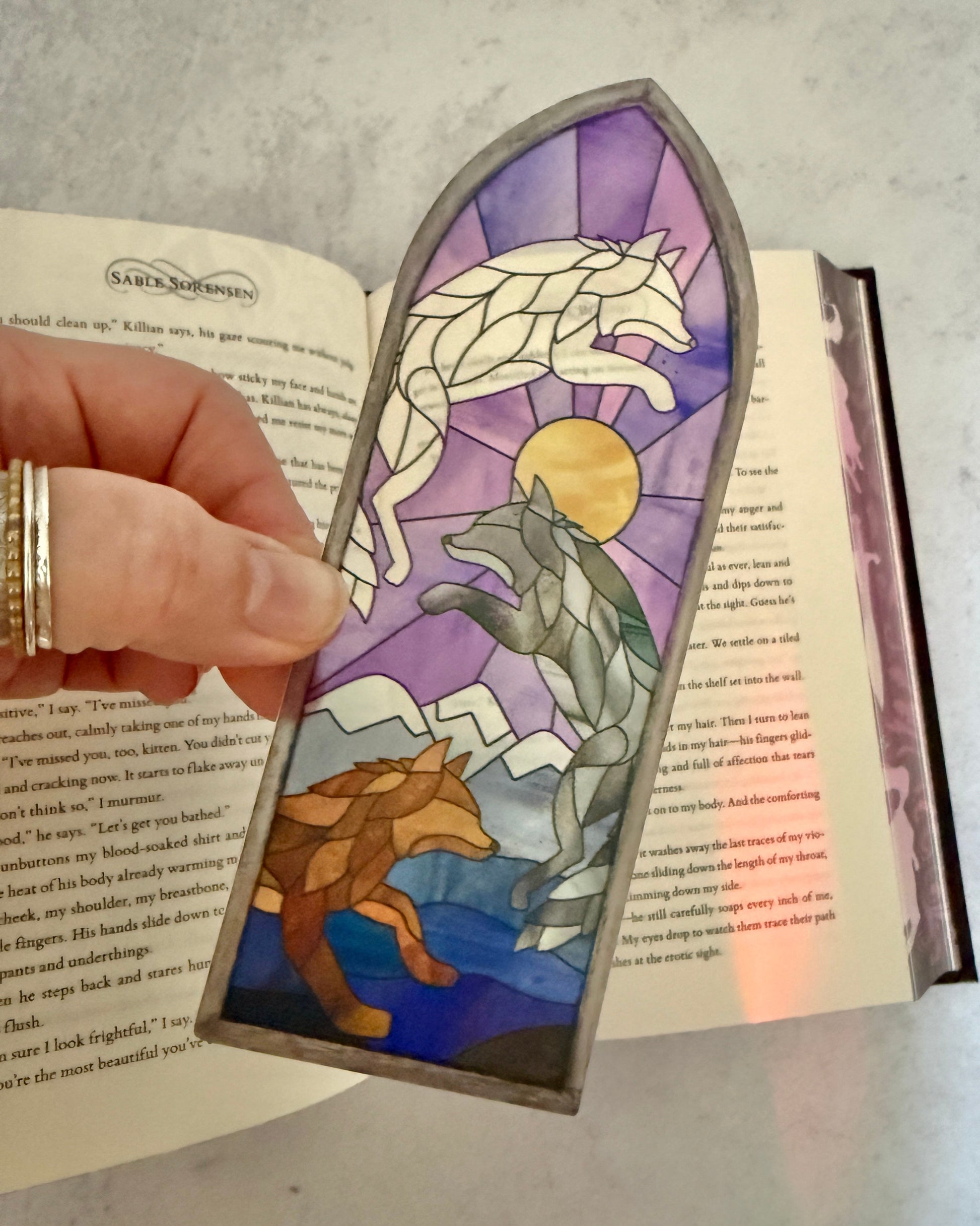 Decorative bookmark with Dire Bound wolf design in a stained glass style on an open book