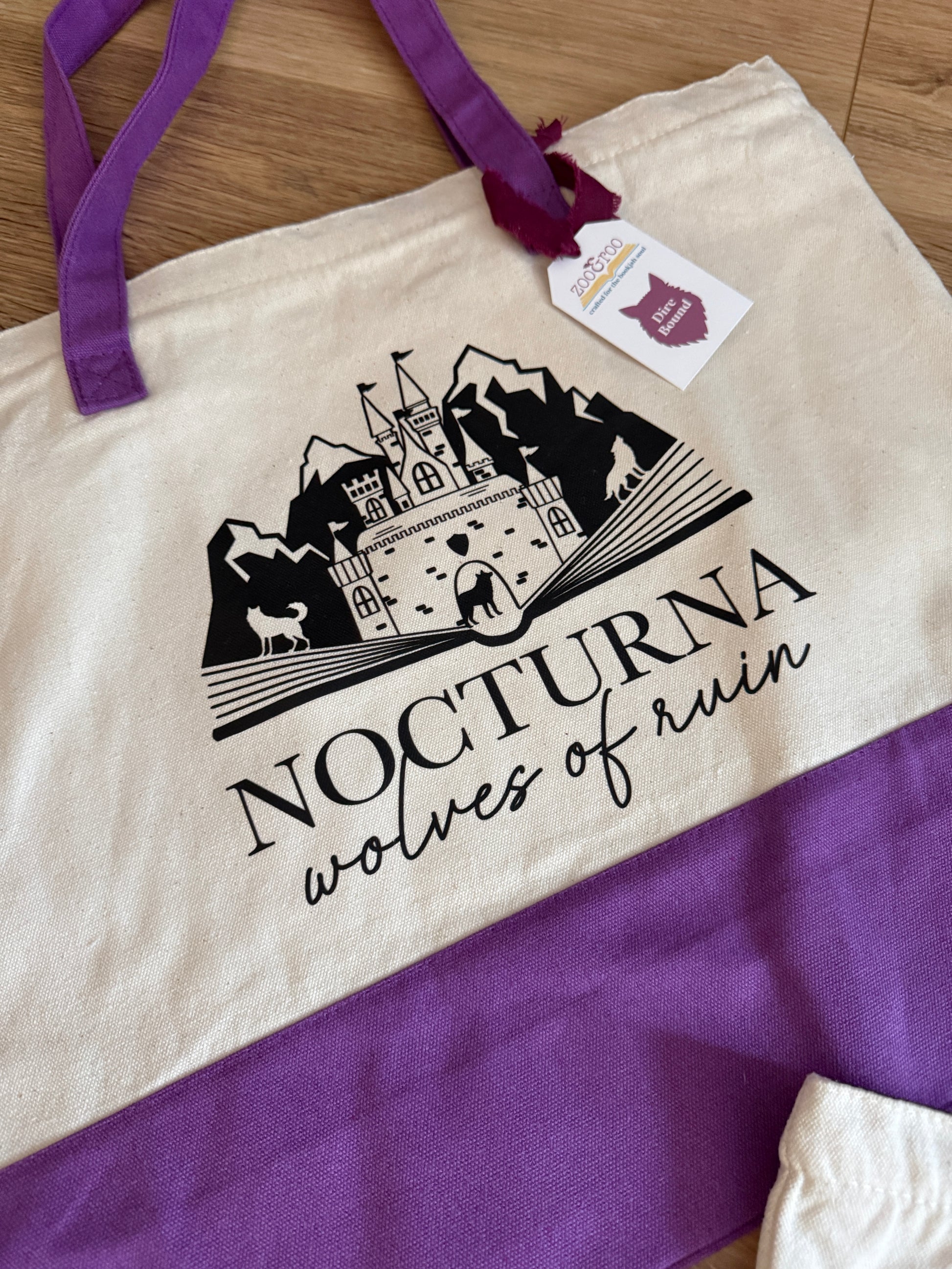 Tote bag with 'Nocturna wolves of ruin' design inspired by Dire Bound by Sable Sorensen on a wooden surface