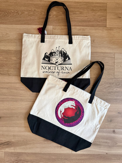 Two tote bags with Nocturna: wolves of ruin designs inspired by Dire Bound by Sable Sorensen on a wooden surface