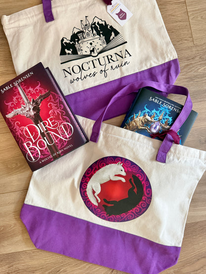 Tote bag with 'Nocturna Wolves of Ruin' branding and Dire Bound books on a wooden surface