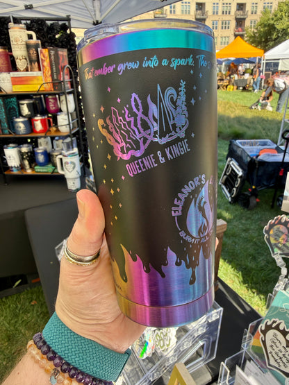 Hand holding the black and rainbow Emarion 20 oz tumbler, showing the Crown of Emarion Queenie & Kingie and Eleanor's Embers original designs