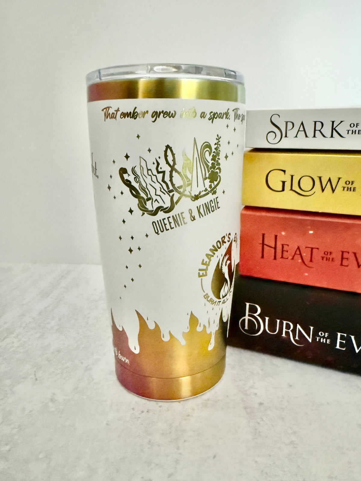 A white and rainbow Emarion 20 oz tumbler, showing the Queenie & Kingie and Eleanor's Embers designs from Burn of the Everflame by Penn Cole