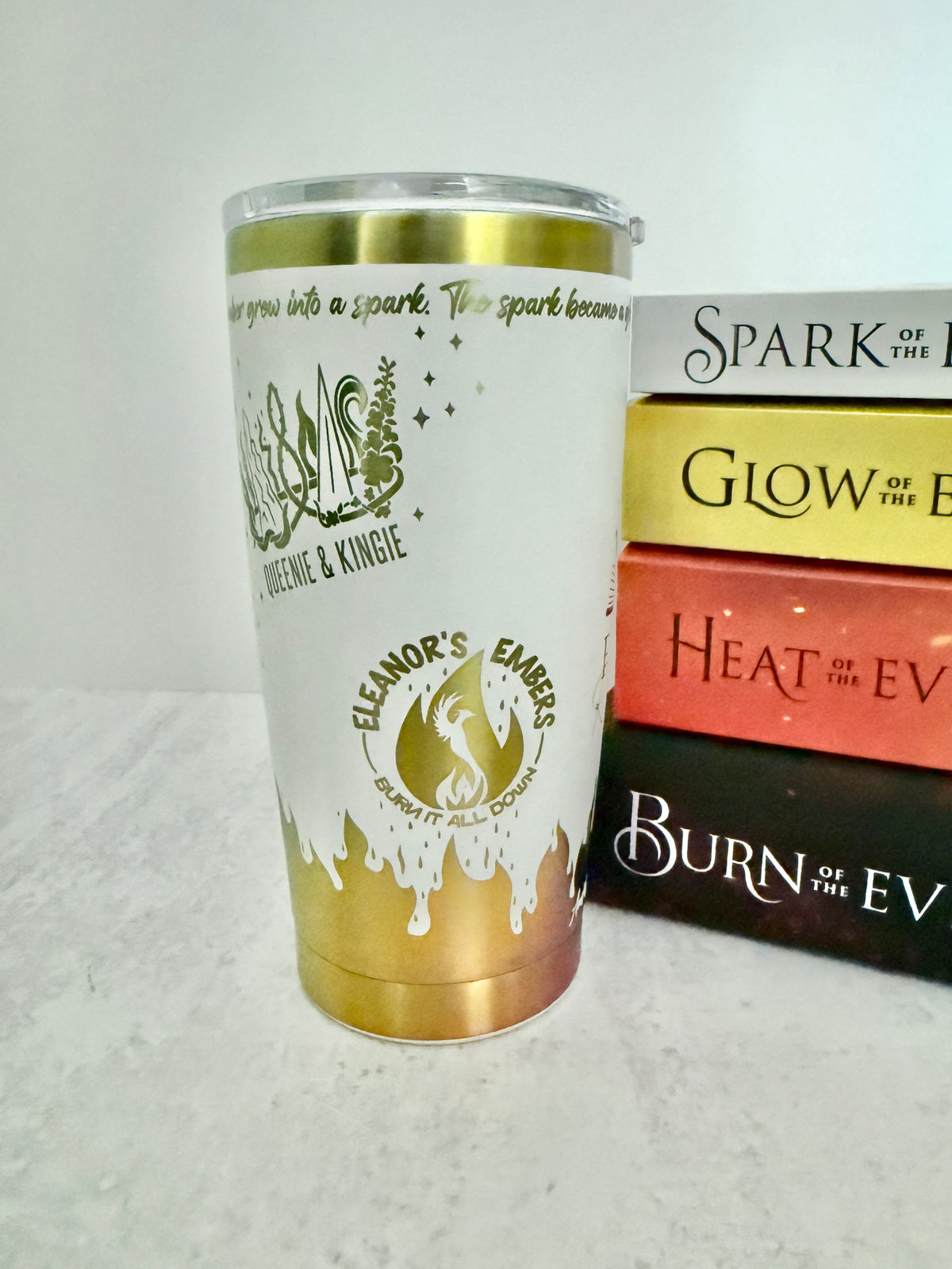 A white and rainbow Emarion 20 oz tumbler, showing the Queenie & Kingie and Eleanor's Embers designs from Burn of the Everflame by Penn Cole