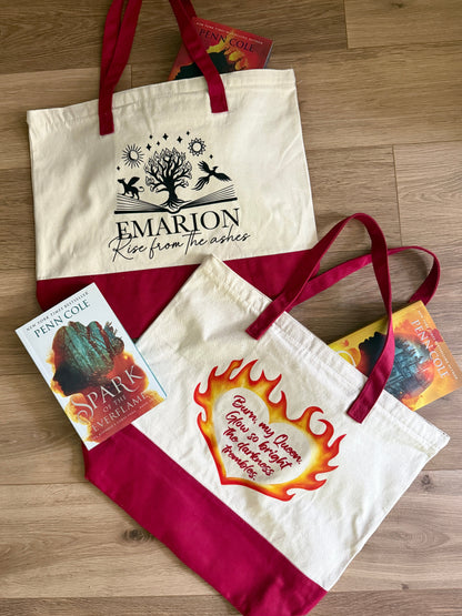 Two Kindred's Curse Saga tote bags with printed designs inspired by Penn Cole's books on a wooden surface. Bags feature quotes "Burn my Queen. Glow so bright the darkness trembles." and "rise from the ashes."