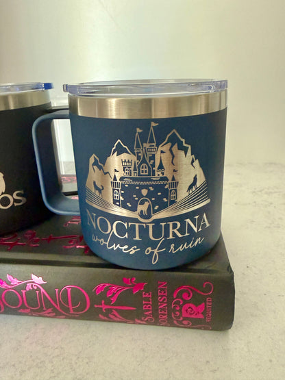 Blue tumbler with 'Nocturna' wolves of ruin castle and mountain design on a Dire Bound book by Sable Sorensen