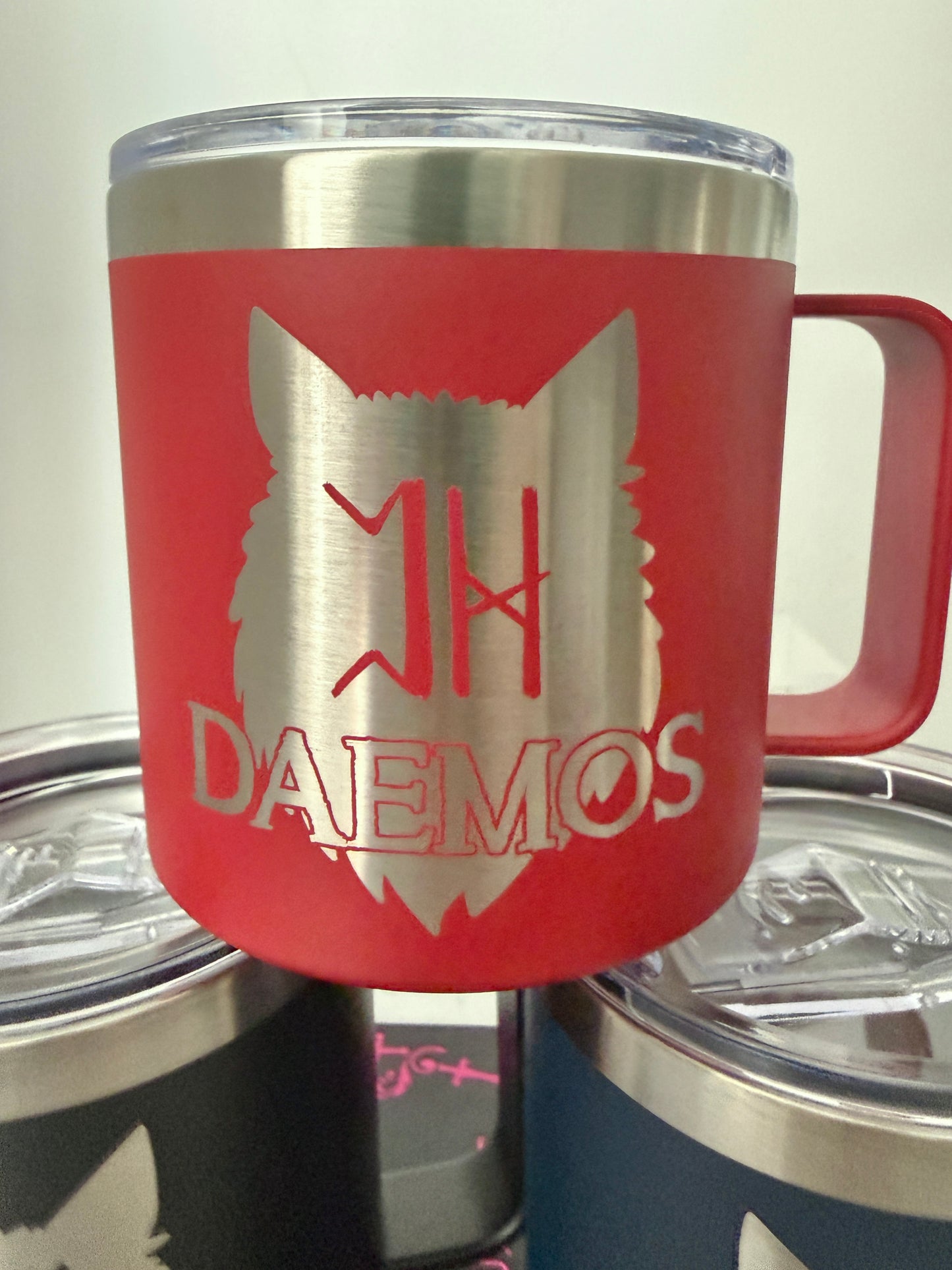 Red camp mug with a wolf design and 'DAEMOS' text on a white background