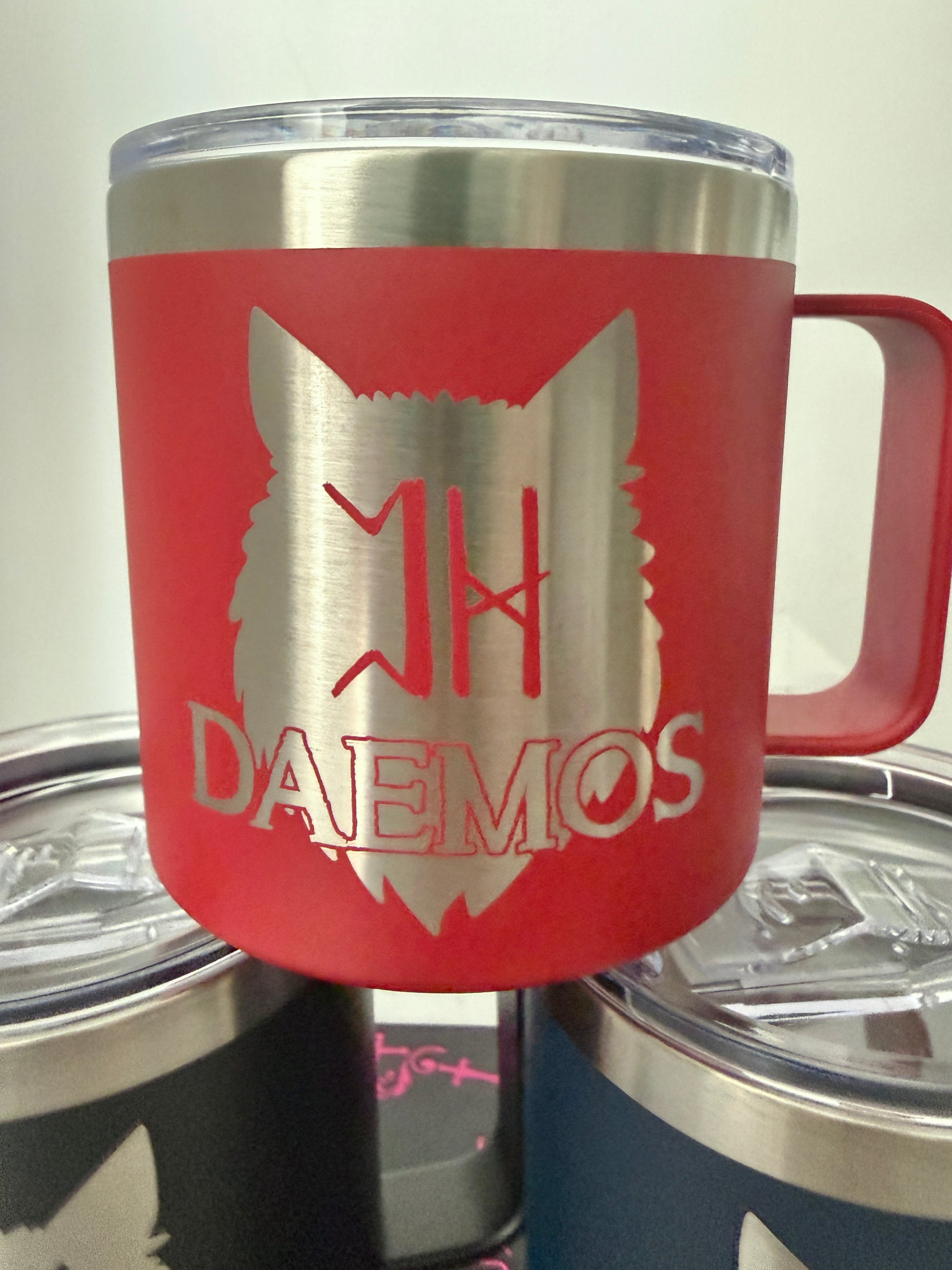 Red camp mug with a wolf design and 'DAEMOS' text on a white background