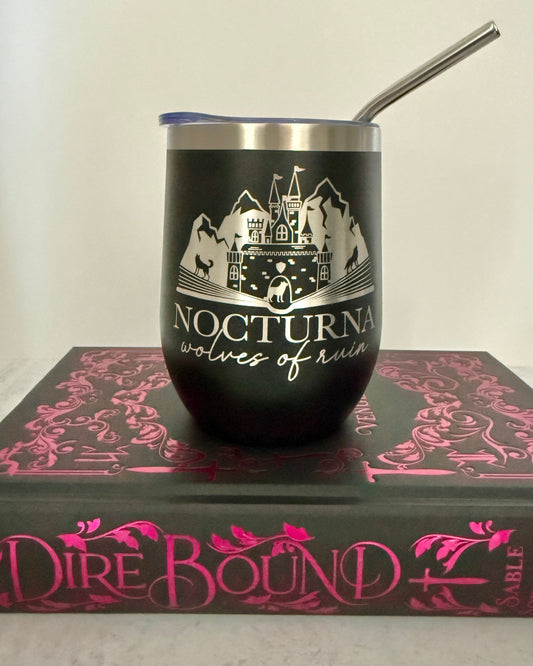 Black tumbler with 'Nocturna Wolves of Ruin' design on a Dire Bound book with pink text.