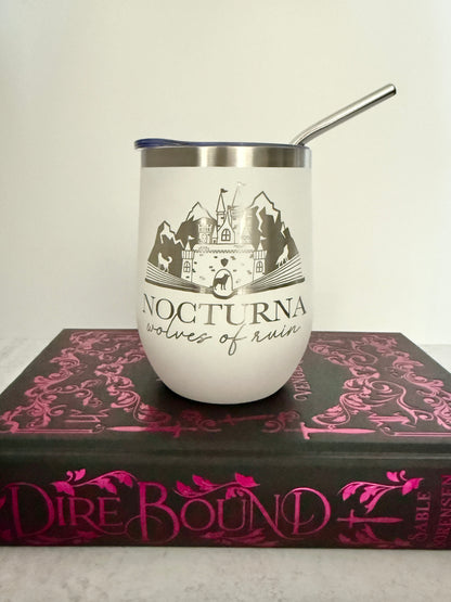 White tumbler with mountain design and 'Nocturna' text on a book titled 'Dire Bound'.