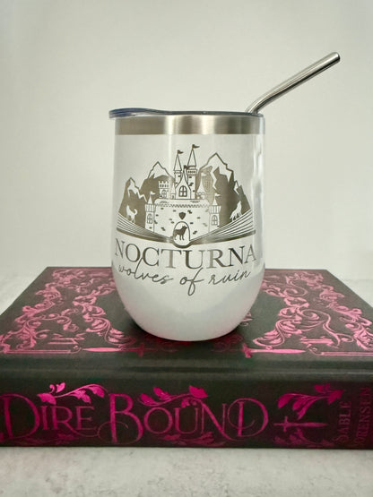 White tumbler with castle design and 'Nocturna: wolves of ruin' text on a book titled 'Dire Bound'.