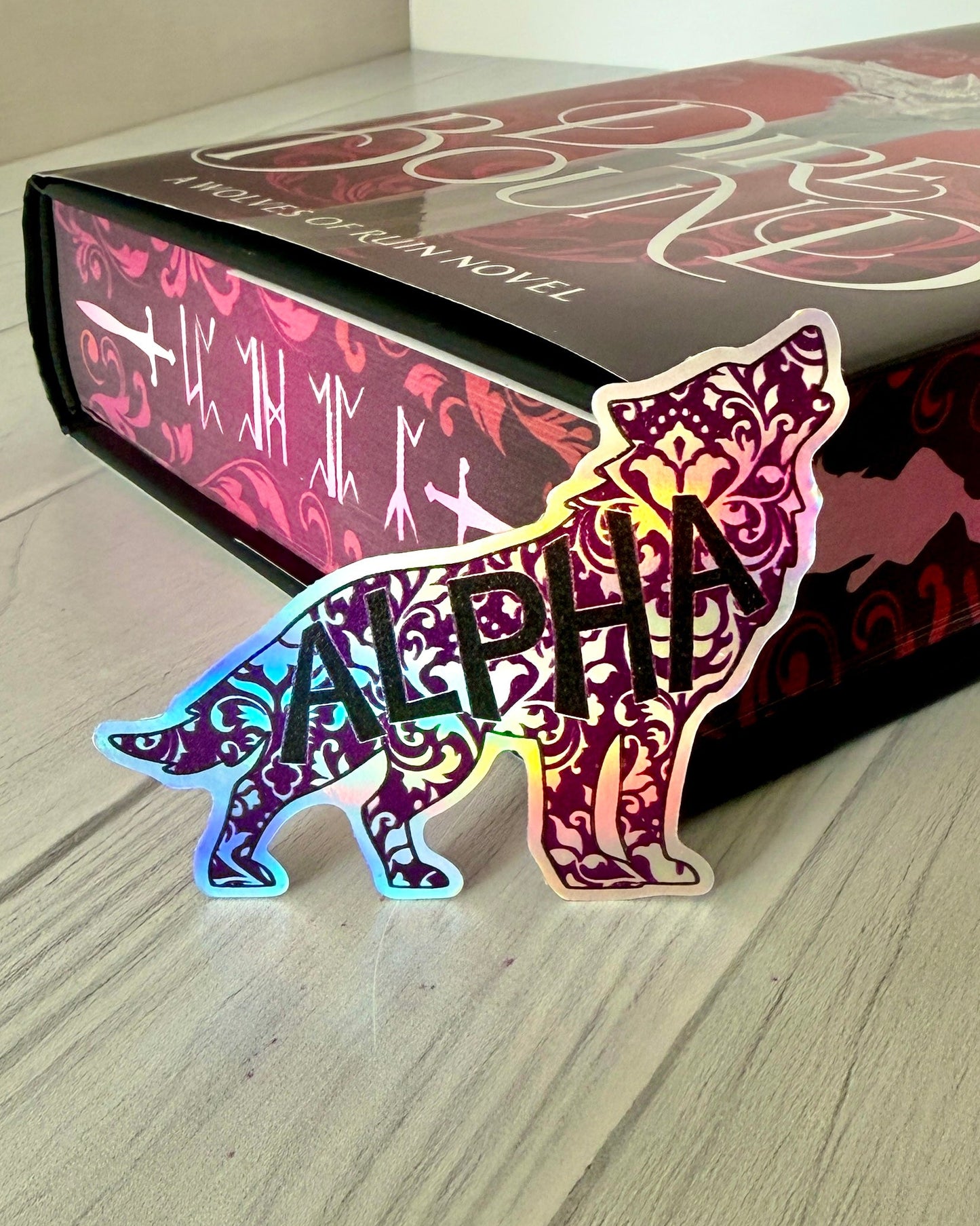 Decorative wolf shaped die cut holographic sticker with 'ALPHA' on a copy of Dire Bound