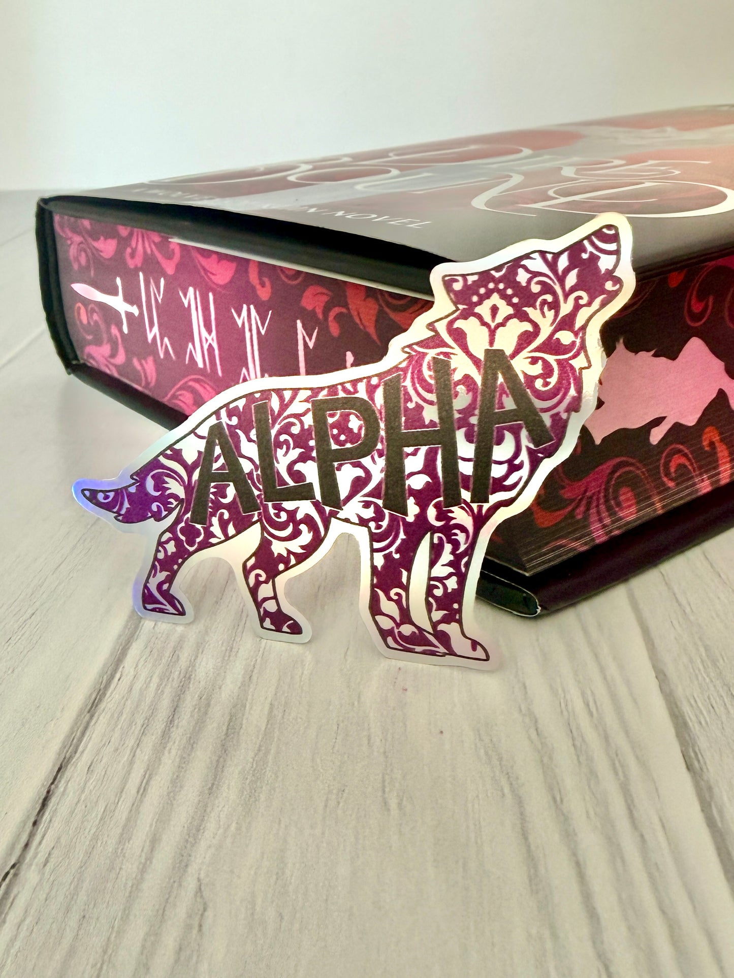 Decorative sticker with wolf design and 'ALPHA' text on a Dire Bound book with sprayed edges.