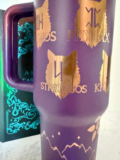Closeup of a purple 40 oz Dire Bound inspired tumbler with gold-engraved wolf pack symbols for Daemos, Phylax, Strategos and Kryptos