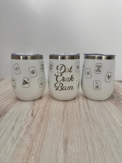 Three white stainless steel insulated mahjong wine tumblers with lids arranged on a light wood surface against a white background. The center tumbler reads 'Dot Crak Bam' engraved with mahjong tiles wrapped around the sides.