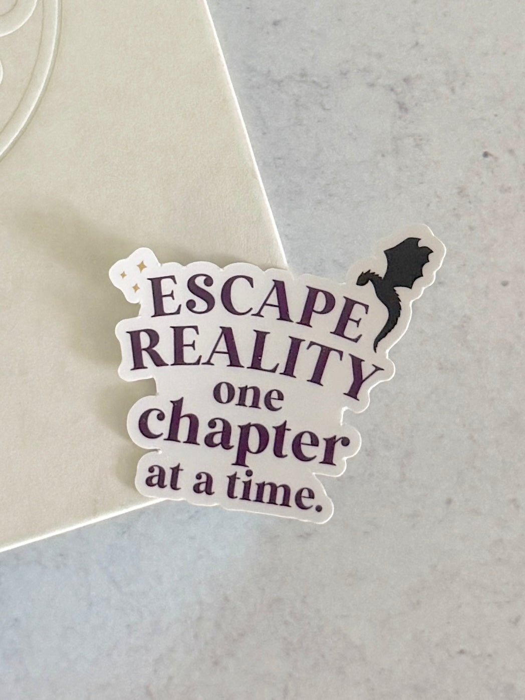 Escape Reality One Chapter at a Time vinyl sticker with dragon silhouette and purple typography on white background