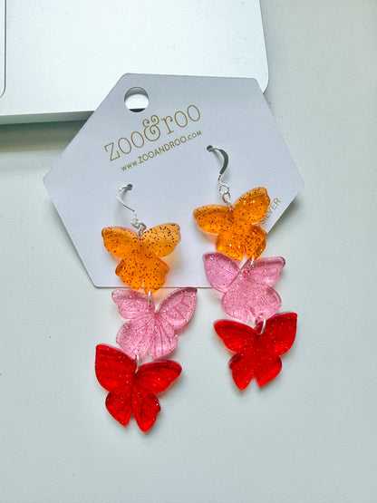 Flíta butterfly earrings inspired by Road of Bones by Demi Winters on a display card with zoo&roo branding, against a white background.