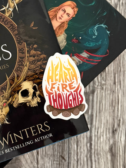 Two books, The Road of Bones and Kingdom of Claw by Demi Winters, stacked with a 'Heart Fire Thoughts' sticker on a wooden surface