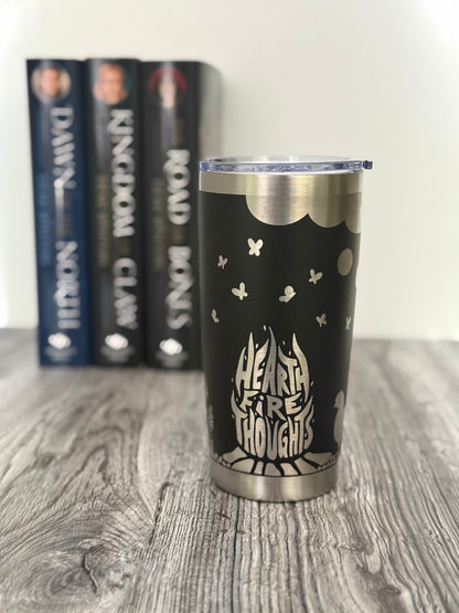 Black tumbler with 'Hearthfire Thoughts' design on a wooden surface with Demi Winters' Ashen series books in the background.