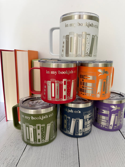 six colorful stainless steel mugs stacked in a pyramid, each engraved with 'in my bookish era,' books and a dragon.
