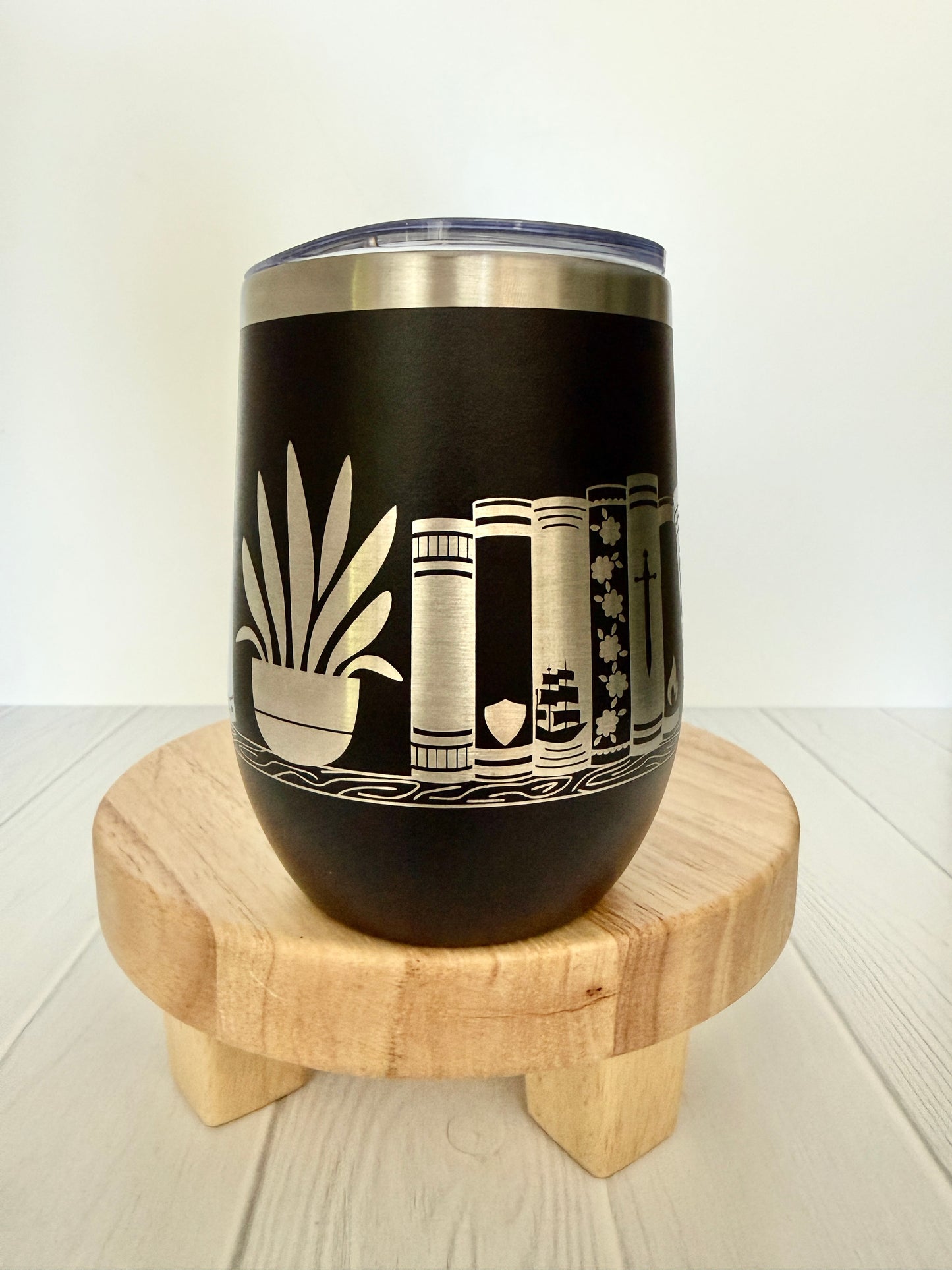 black wine tumbler engraved with books on a book shelf
