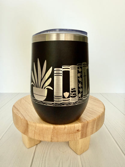 black wine tumbler engraved with books on a book shelf