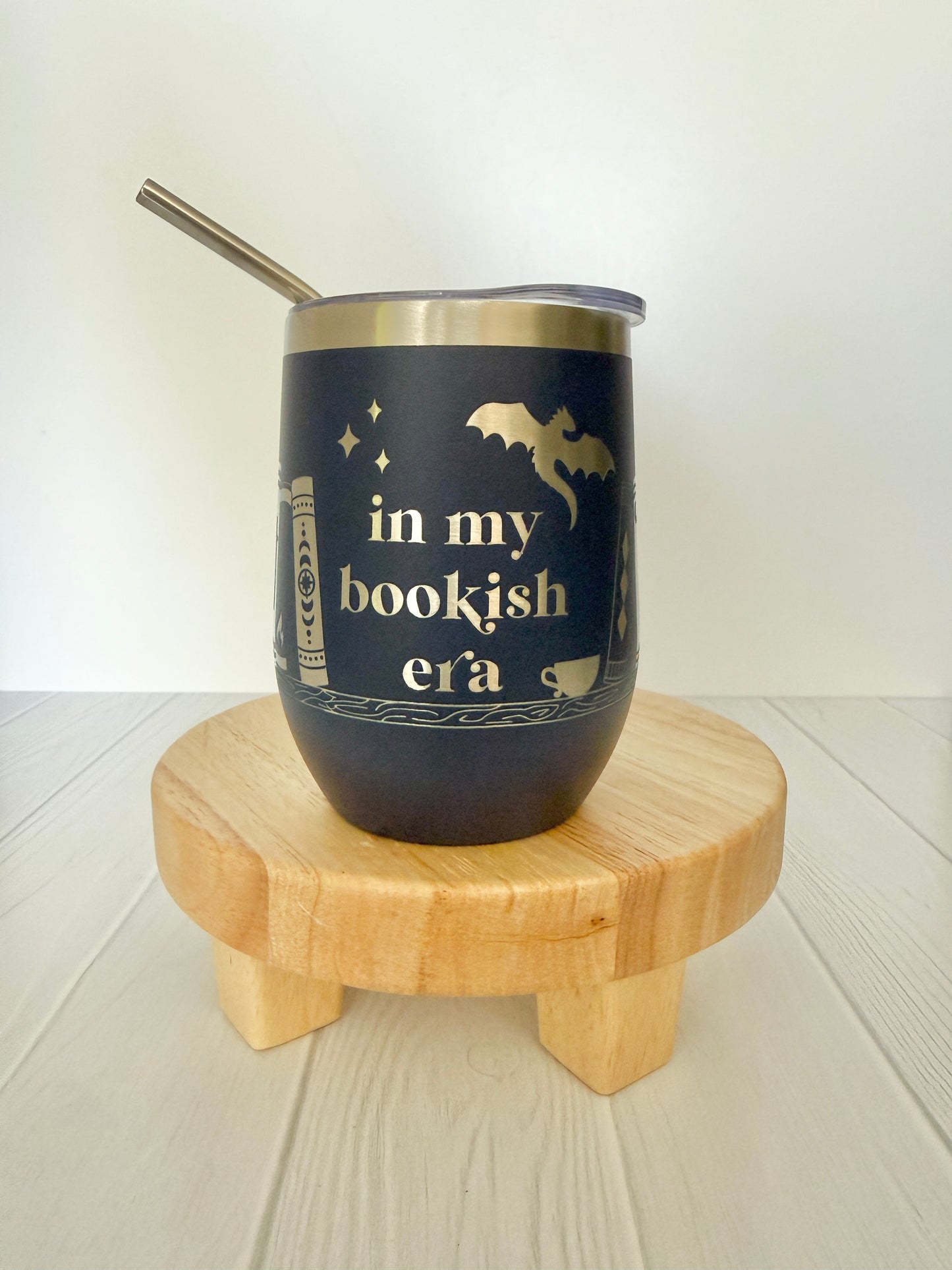 navy wine tumbler engraved with "in my bookish era" and books on a book shelf and a dragon