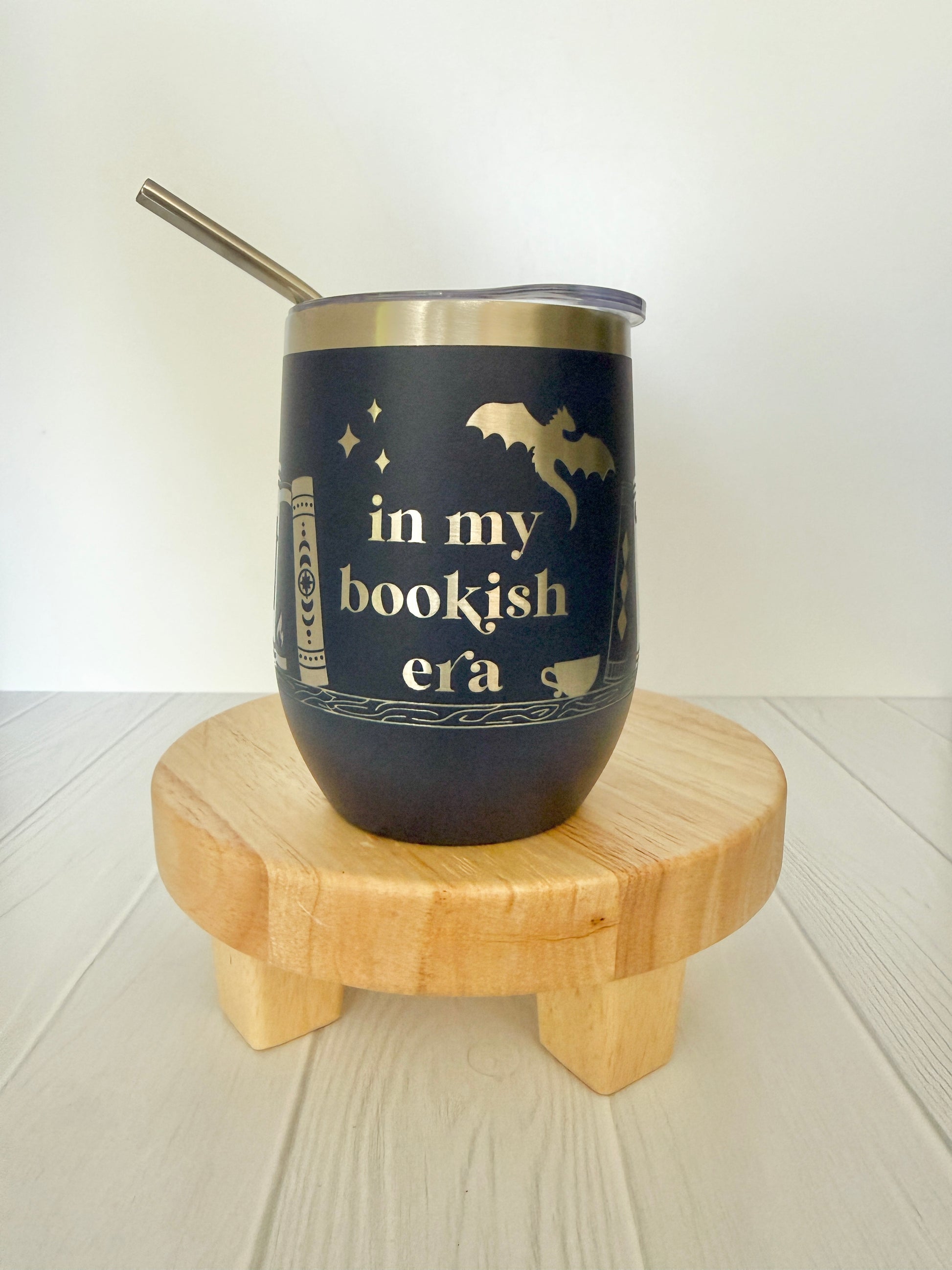 navy wine tumbler engraved with "in my bookish era" and books on a book shelf and a dragon