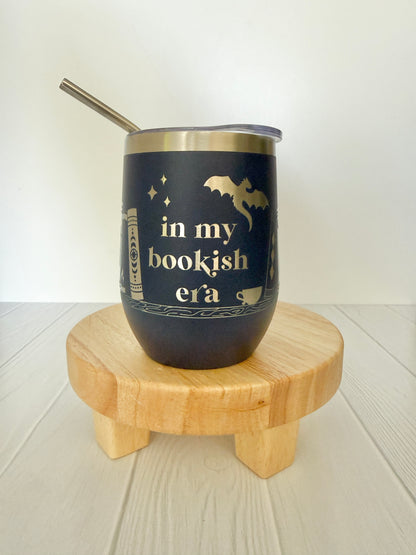 navy wine tumbler engraved with "in my bookish era" and books on a book shelf and a dragon