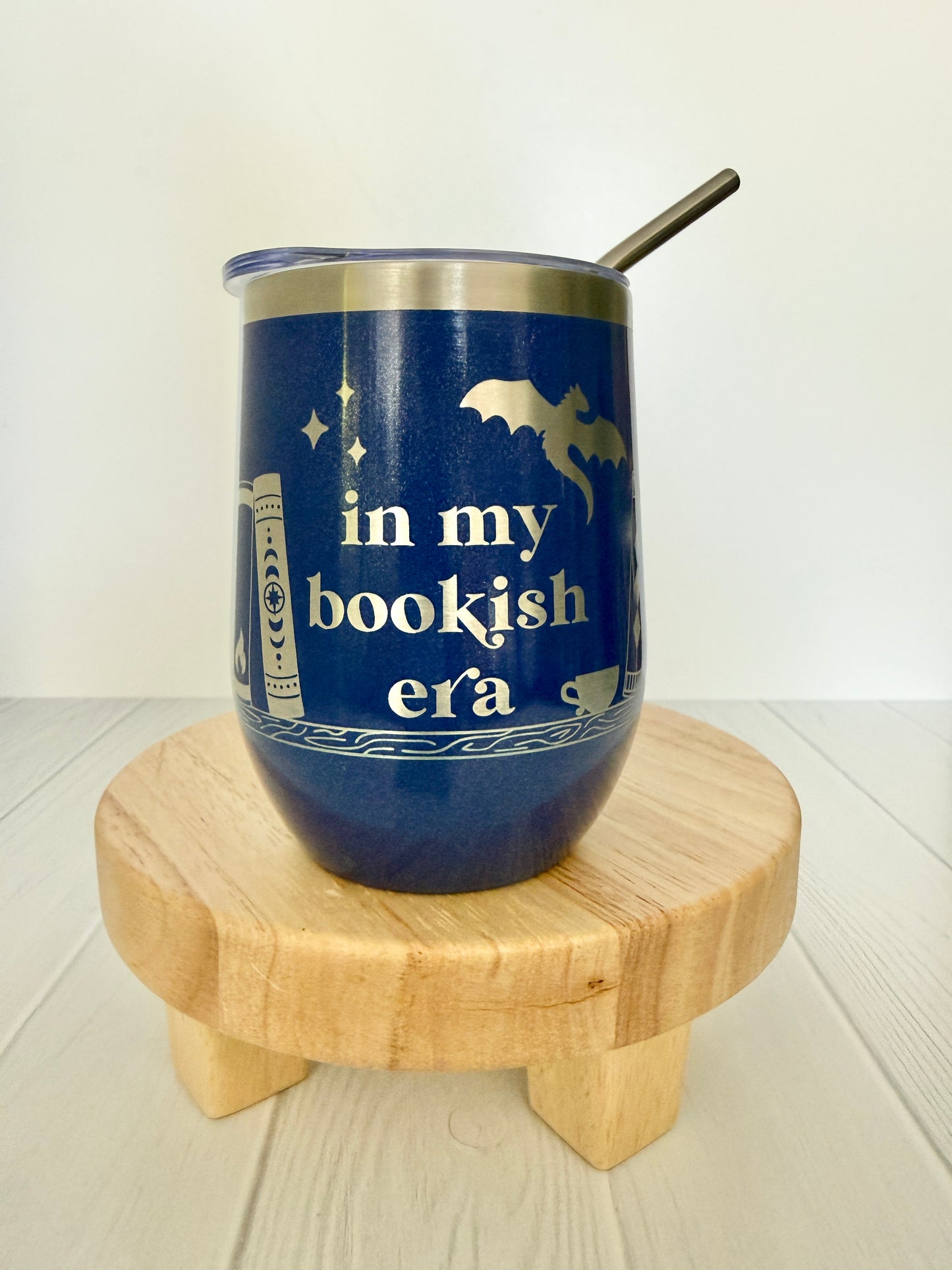 Blue tumbler with 'in my bookish era' text on a wooden stand
