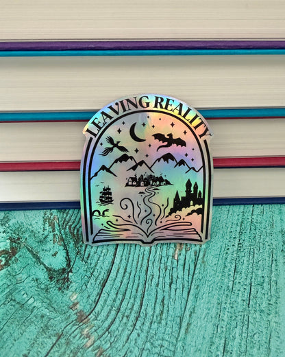 Holographic 'Leaving Reality' sticker featuring a book and fantasy elements