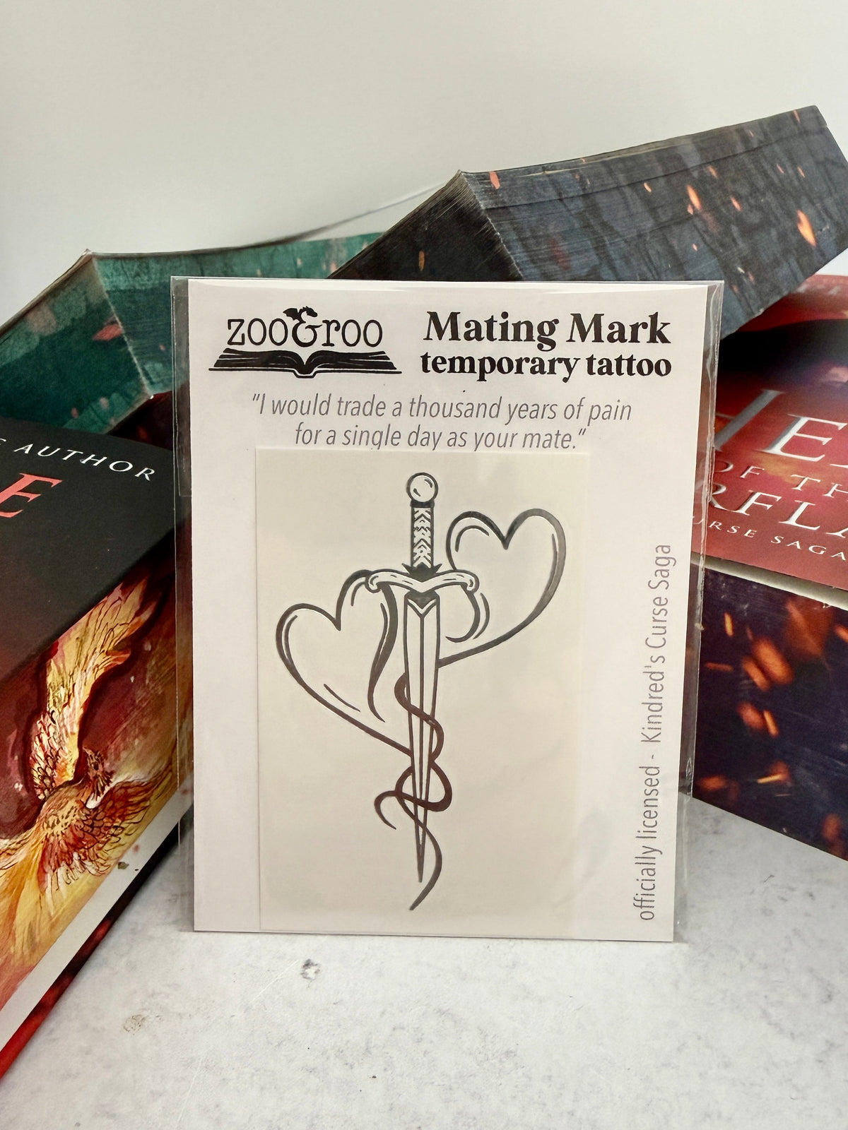 Mating mark temporary tattoo design showing two hearts forged into a dagger, displayed against Kindred's Curse Saga paperbacks