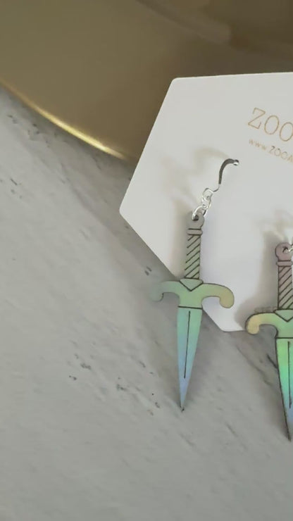 A pair of iridescent vegan leather dagger earrings, displayed on a white zoo&roo brand card against a light gray wood background.