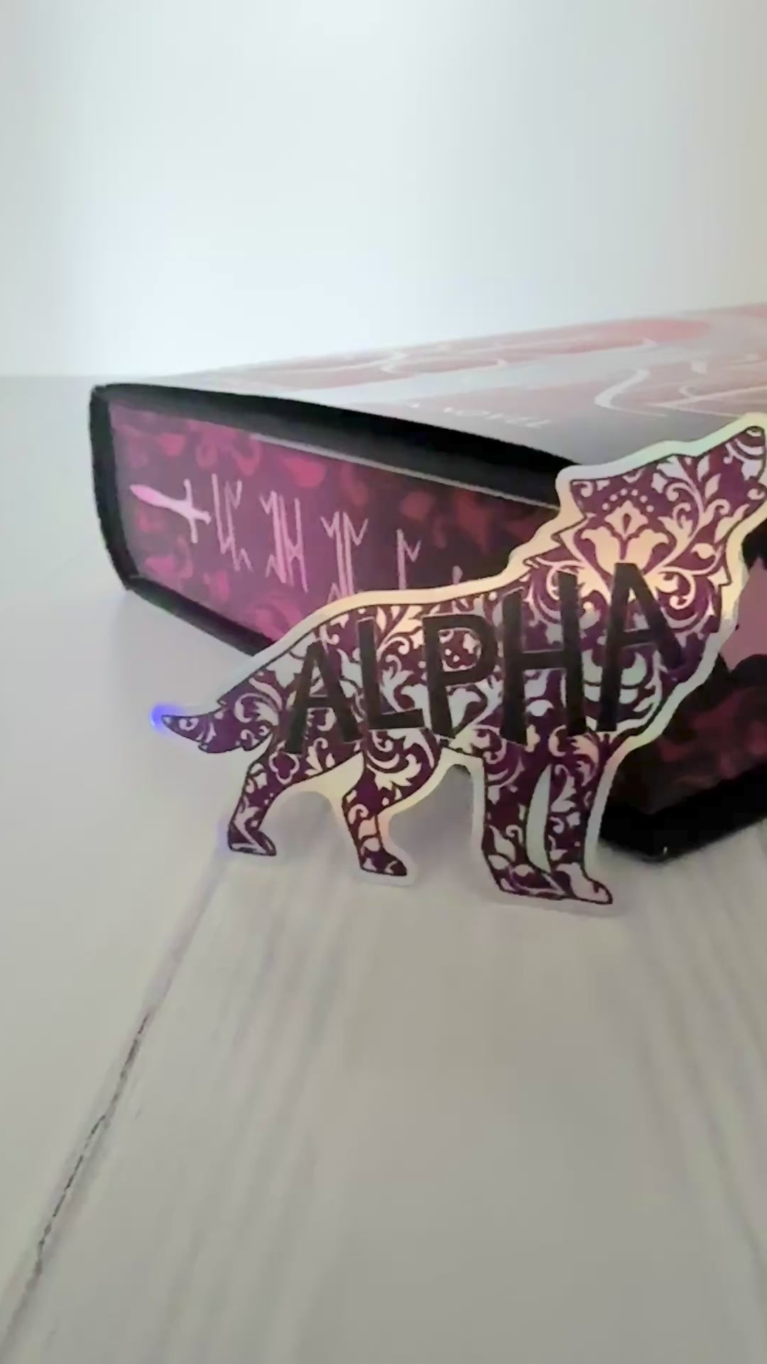 Holographic die cut wolf shaped sticker in a damask floral design with "alpha" in a bold font.