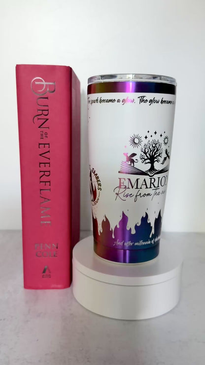 Slow turn of a white and rainbow iridescent 20 oz Emarion tumbler with Everflame tree, phoenix and gryvern exploding from an open book and other world elements from  the Kindred's Curse Saga, next to a copy of Burn of the Everflame