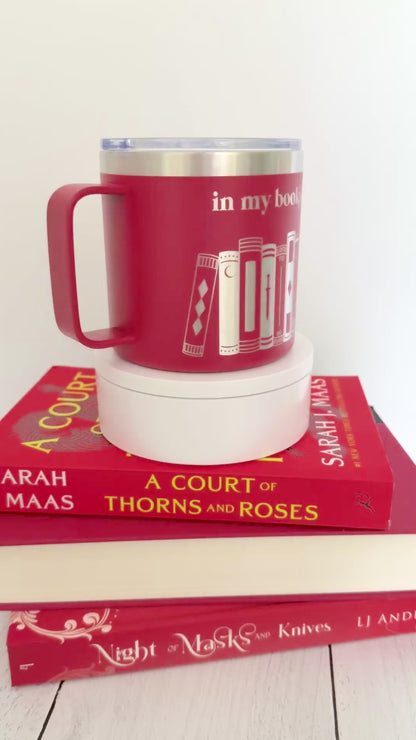 Red stainless steel mug with 'in my bookish era' and books engraved around it, set on top of a stack of red books.