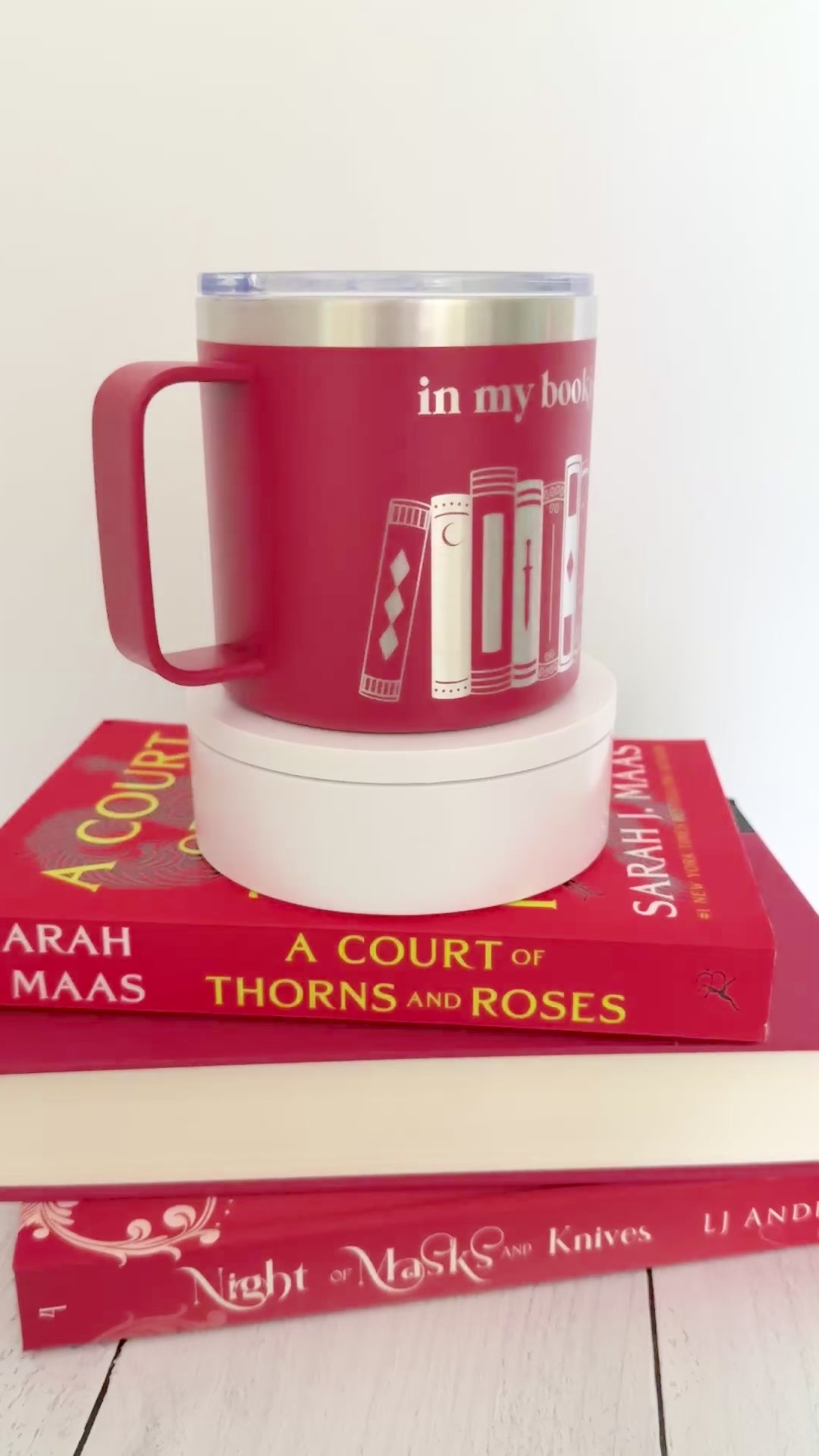 Red stainless steel mug with 'in my bookish era' and books engraved around it, set on top of a stack of red books.