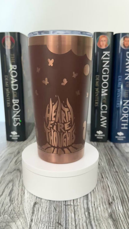 A brown and gold tumbler with 'Hearthfire Thoughts' design inspired by The Road of Bones Ashen series books by Demi Winters