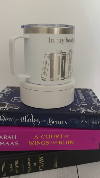 White stainless steel mug with 'in my bookish era' and books engraved around it, set on top of a stack of books.