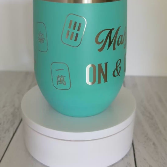 Mahjong wine tumbler with 'mahj on and on' text and mahjong tiles wrapped around the aqua tumbler.