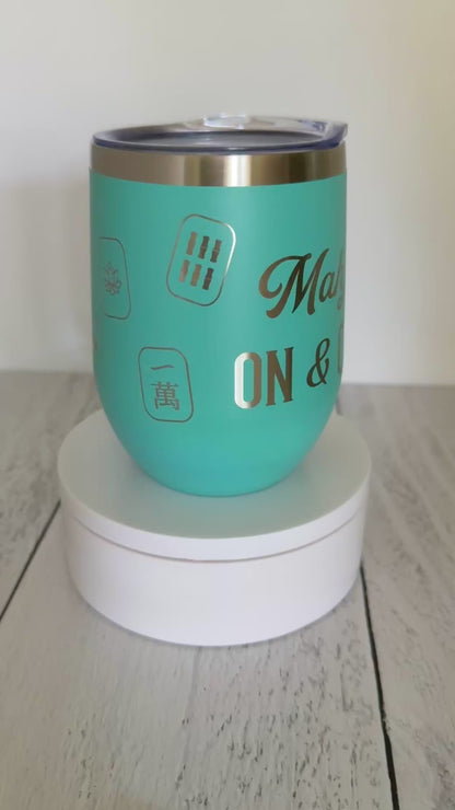Mahjong wine tumbler with 'mahj on and on' text and mahjong tiles wrapped around the aqua tumbler.