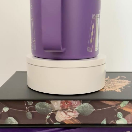 Purple stainless steel mug with 'in my bookish era' and books engraved around it, set on top of a stack of purple and black books.