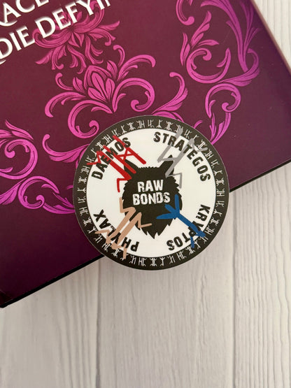 Circular sticker with "rawbonds" and a wolf head in the center, surrounded by pack symbols from Dire Bound on a decorative purple book background