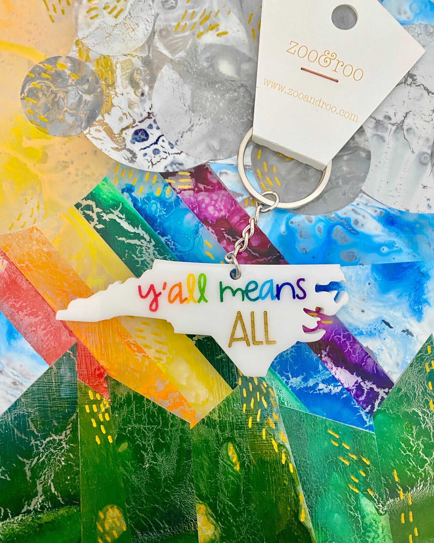 Keychain with 'y'all means all' tag on a colorful abstract background