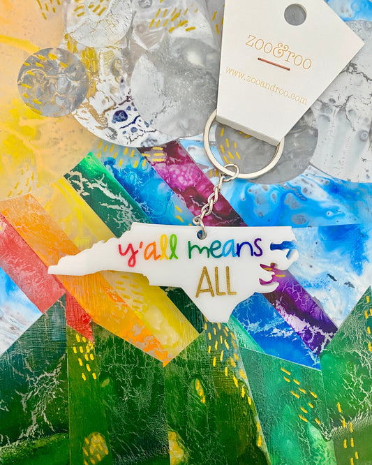 Keychain with 'y'all means all' tag on a colorful abstract background