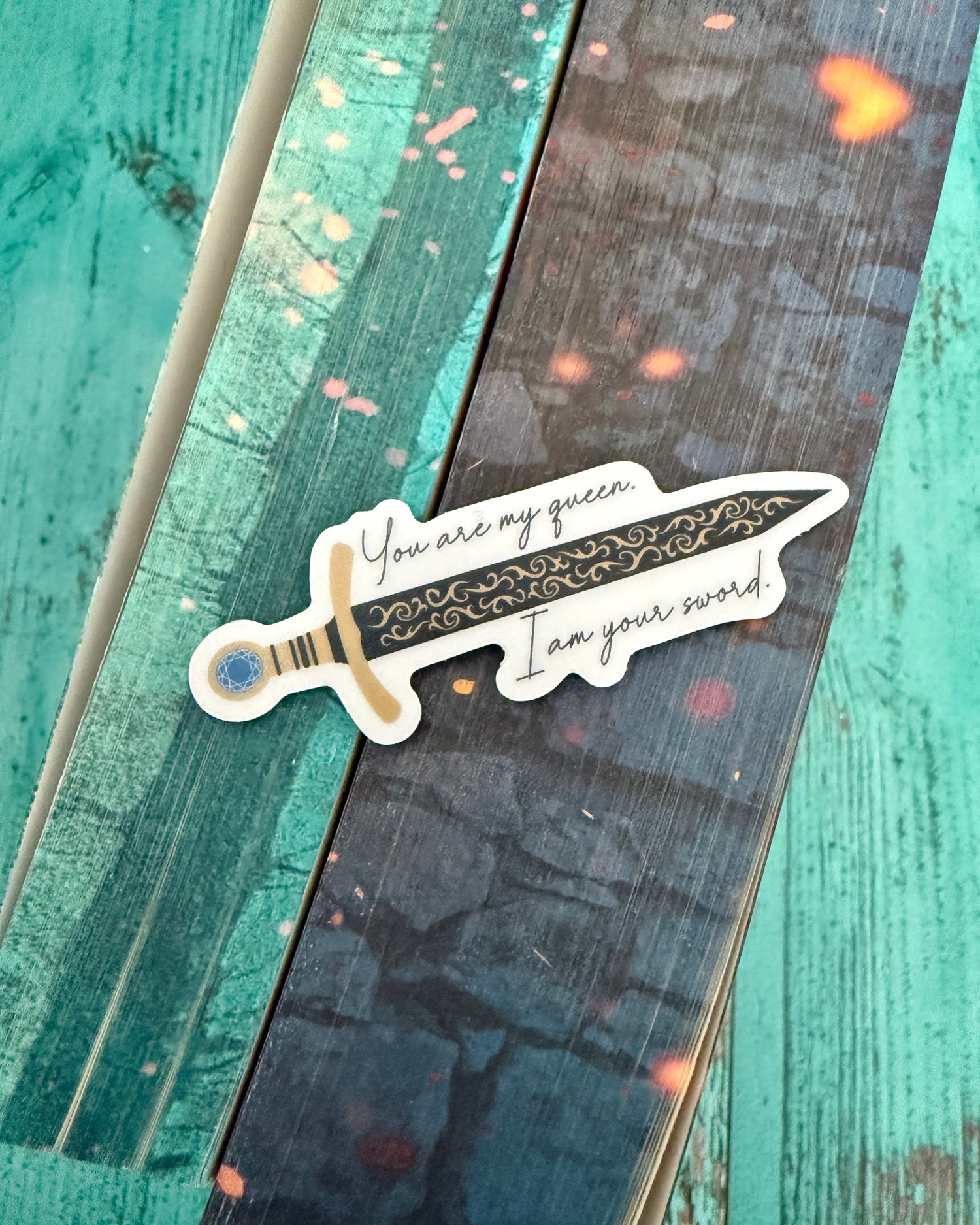 Sticker from The Kindred's Curse Saga featuring an onyx sword with gold scrollwork and the vow "You are my queen. I am your sword." Spark of the Everflame by Penn Cole.